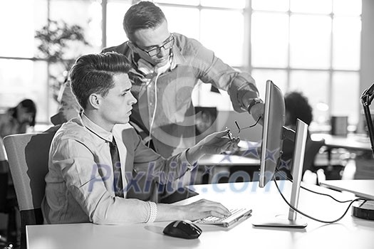 two business people using computer preparing for next meeting and discussing ideas with colleagues in the background two business people using computer preparing for next meeting and discussing ideas with colleagues in the background