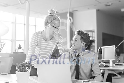 two business people using laptop preparing for next meeting and discussing ideas with colleagues in the background two business people using laptop preparing for next meeting and discussing ideas with colleagues in the background