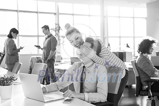 two business people using laptop preparing for next meeting and discussing ideas with colleagues in the background two business people using laptop preparing for next meeting and discussing ideas with colleagues in the background