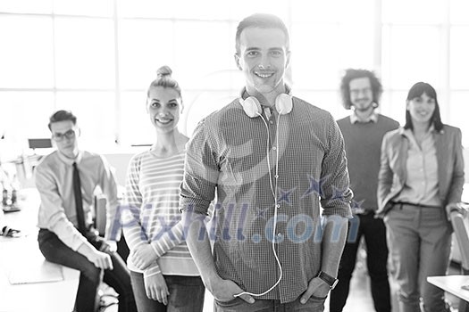 Portrait of smiling young casuall businessman with colleagues in background at the office Portrait of smiling young casuall businessman with colleagues in background at the office