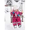 child outdoor in park at winter day with fresh snow, cute little girl swing and playing