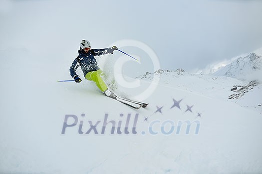 skier skiing downhill on fresh powder snow  with sun and mountains in background