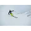 skier skiing downhill on fresh powder snow  with sun and mountains in background