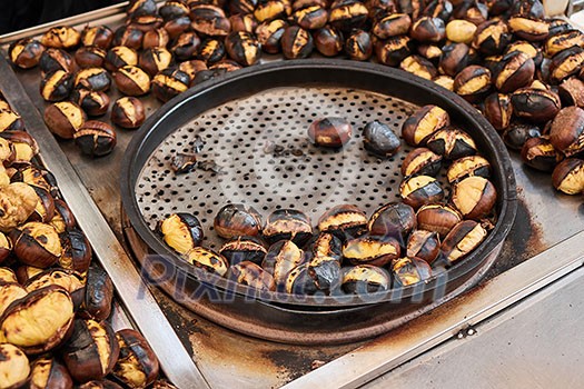 Fried chestnuts on the street. Street food. Roasted chestnuts served in a special perforated chestnut pan. Fried chestnuts on the street. Street food. Roasted chestnuts served in a special perforated chestnut pan.