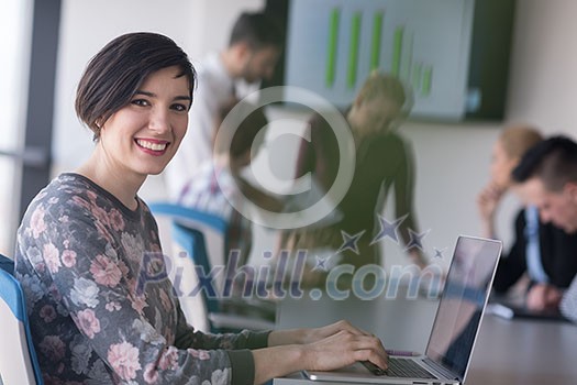 young business woman at modern startup office interior working on laptop computer, blured team in meeting, people group in background young business woman at modern startup office interior working on laptop computer, blured team in meeting, people group in background