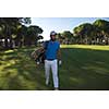 handsome middle eastern golf player carrying and bag  and walking at course on beautiful morning sunrise