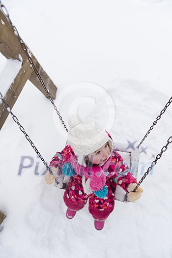 child outdoor in park at winter day with fresh snow, cute little girl swing and playing child outdoor in park at winter day with fresh snow, cute little girl swing and playing