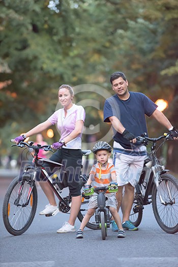portrait of happy young family with bicycles in park at night portrait of happy young family with bicycles in park at night