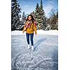 Young woman ice skating outdoors on a pond on a freezing winter day (color toned image; motion blurred image)
