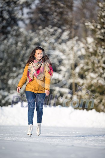 Young woman ice skating outdoors on a pond on a freezing winter day (color toned image; motion blurred image) Young woman ice skating outdoors on a pond on a freezing winter day (color toned image; motion blurred image)