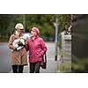 Senior woman walking her little dog on a city street with her granddaughter; looking happy and relaxed (shallow DOF)