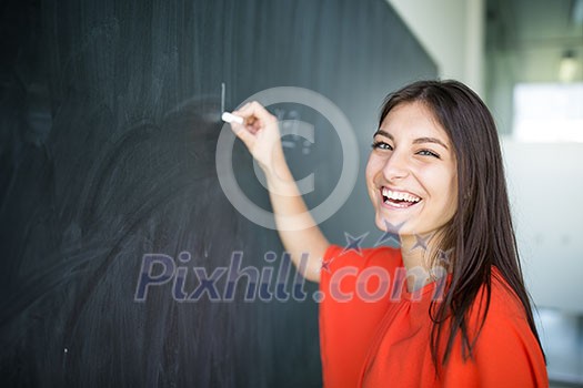Pretty, young college student writing on the chalkboard/blackboard during a math class Pretty, young college student writing on the chalkboard/blackboard during a math class