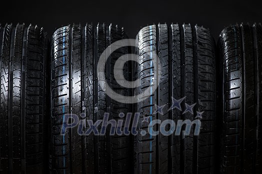 Stack of brand new high performance car tires on clean low-key black studio background Stack of brand new high performance car tires on clean low-key black studio background