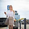 Young female passenger at the airport, walking to he departure terminal from a parking lot (color toned image)