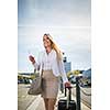 Young female passenger at the airport, walking to he departure terminal from a parking lot (color toned image)