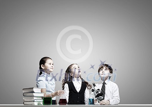Three cute children at chemistry lesson making experiments Three cute children at chemistry lesson making experiments