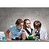 Three cute children at chemistry lesson making experiments