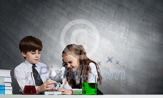 Two cute children at chemistry lesson making experiments Two cute children at chemistry lesson making experiments