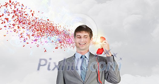 Smiling businessman talking on red phone handset Smiling businessman talking on red phone handset