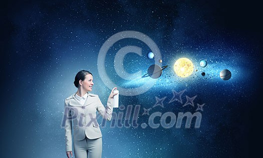 Young businesswoman spraying space planets from aerosol balloon Young businesswoman spraying space planets from aerosol balloon
