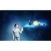 Young businesswoman spraying space planets from aerosol balloon