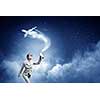 Young woman in suit and glasses spraying airplane in sky
