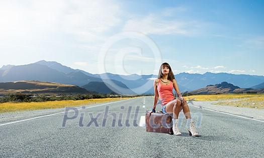 Traveler woman sits on retro suitcase and waiting for car