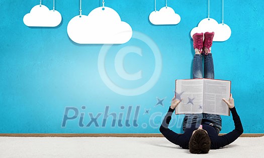 Young girl laying by the wall and reading book