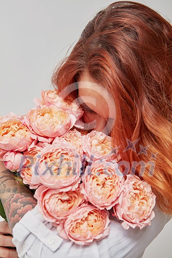 red-haired girl sniffing a bouquet of pink roses, the concept of a valentine's day red-haired girl sniffing a bouquet of pink roses, the concept of a valentine's day