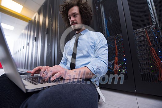 Male IT engineer working on a laptop in server room at modern data center Male IT engineer working on a laptop in server room at modern data center