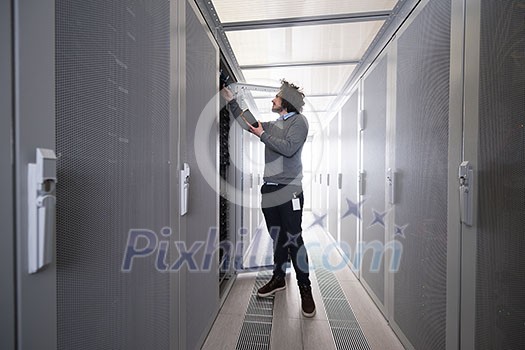 young IT technician using digital cable analyzer on server in large data center young IT technician using digital cable analyzer on server in large data center