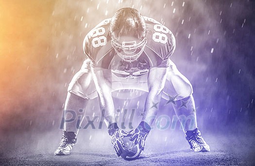 American football player starting football game on big modern american football field with lights and flares at night American football player starting football game on big modern american football field with lights and flares at night