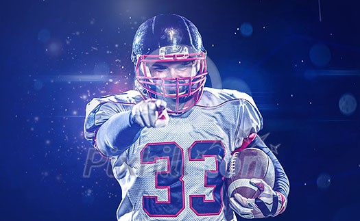 portrait of confident American football player holding ball while standing on field at night portrait of confident American football player holding ball while standing on field at night