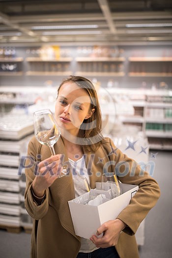 Pretty, young woman in a home supply store choosing the right glasses for her wine addiction (color toned image; shallow DOF) Pretty, young woman in a home supply store choosing the right glasses for her wine addiction (color toned image; shallow DOF)