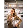 Pretty, young woman in a home supply store choosing the right glasses for her wine addiction (color toned image; shallow DOF)