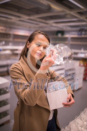 Pretty, young woman in a home supply store choosing the right glasses for her wine addiction (color toned image; shallow DOF) Pretty, young woman in a home supply store choosing the right glasses for her wine addiction (color toned image; shallow DOF)