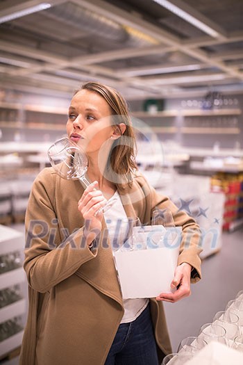 Pretty, young woman in a home supply store choosing the right glasses for her wine addiction (color toned image; shallow DOF) Pretty, young woman in a home supply store choosing the right glasses for her wine addiction (color toned image; shallow DOF)