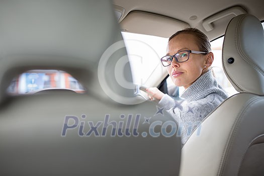 Woman driving a car - female driver at a wheel of a modern car, looking happy, smiling with a relaxed smile (shallow DOF; color toned image) Woman driving a car - female driver at a wheel of a modern car, looking happy, smiling with a relaxed smile (shallow DOF; color toned image)