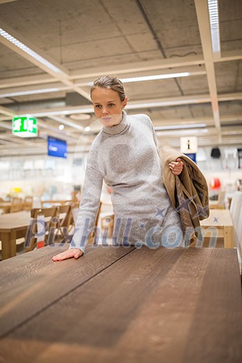 Pretty, young woman choosing the right furniture for her apartment in a modern home furnishings store (color toned image; shallow DOF) Pretty, young woman choosing the right furniture for her apartment in a modern home furnishings store (color toned image; shallow DOF)