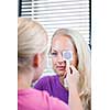 optometry concept - pretty, young female patient having her eyes examined by an eye doctor (color toned image; shallow DOF)