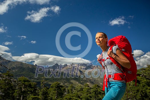Pretty, female hiker in high mountains with her giant backpack, getting ready for some hiking Pretty, female hiker in high mountains with her giant backpack, getting ready for some hiking