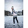 Young woman ice skating outdoors on a pond on a freezing winter day (color toned image; motion blurred image)