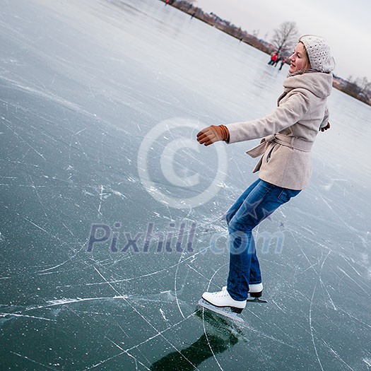 Young woman ice skating outdoors on a pond on a freezing winter day