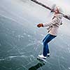 Young woman ice skating outdoors on a pond on a freezing winter day