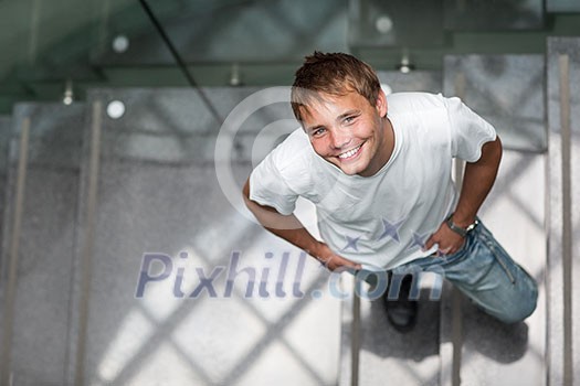 Handsome young man in a staircase, looking up, looking happy and motivated (color toned image) Handsome young man in a staircase, looking up, looking happy and motivated (color toned image)