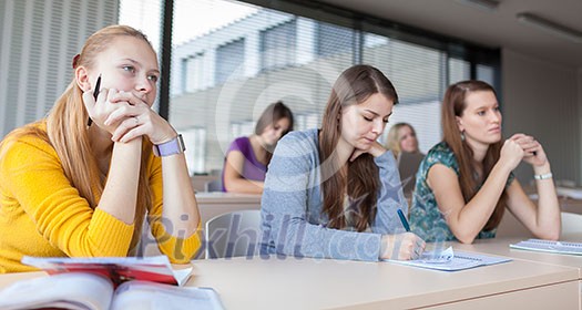 Students in classroom - young pretty female college student sitting in a classroom full of students during class (color toned image; shallow DOF) Students in classroom - young pretty female college student sitting in a classroom full of students during class (color toned image; shallow DOF)
