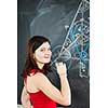 Portrait of a pretty young college student writing on the blackboard during a maths class (color toned image)