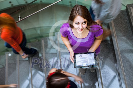 At the university/college - Students rushing up and down a busy stairway - confident pretty young female student looking upwards At the university/college - Students rushing up and down a busy stairway - confident pretty young female student looking upwards