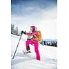 Pretty, young woman snowshoeing in high mountains, enjoying splendid winter weather with abundance of snow