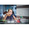 Pretty, young woman eating sushi in a restaurant, having her lunch break, enjoying the food, pausing for a while from her busy corporate/office life (color toned image)